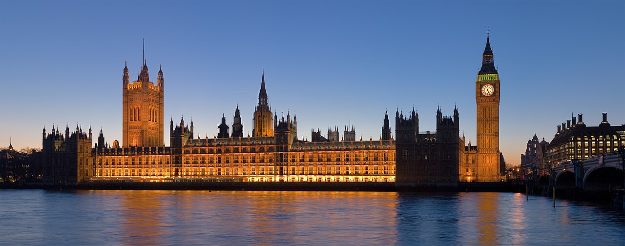 The Palace of Westminster illuminated beside the River Thames.